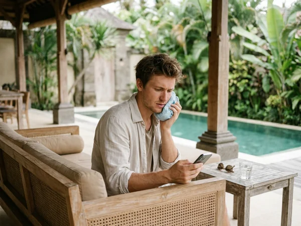 Traveller with toothache sending an urgent appointment request from a villa terrace